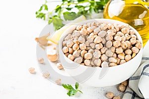 Chickpeas in white bowl at light kitchen table.