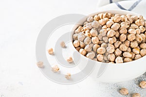 Chickpeas in white bowl at light kitchen table.