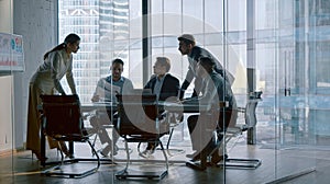 Chief corporate manager talking with team at desk in meeting room