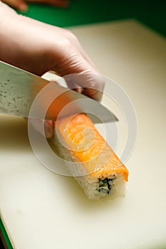chief`s hands cutting sushi roll.