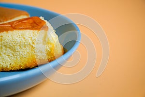 Chiffon cake with young coconut on blue plate, orange background