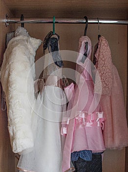 Chiffonier with children`s things, children`s dress dresses, things for the girl hang on a hanger photo