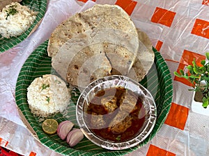 Chiken Thali from an indian cuisine, food platter consists of mutton curry, roti and onions served in disposable plate