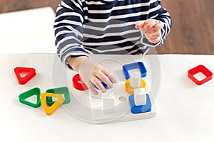 Child 1,5 years old sitting at the table and playing with a developing toy, Montessori technique, the child`s hands are busy play