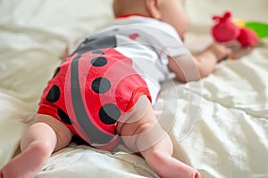 A child of 2 months crawls on the bed to the first toy. Stimulation of crawling. Teaching a child up to six months.