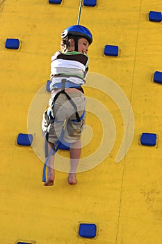 A child abseilling down a climbing wall