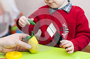 A child with an adult pear sculpts from clay