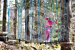 Child in adventure park. Kids climbing rope trail.