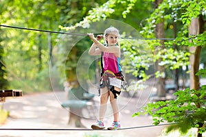 Child in adventure park. Kids climbing rope trail.