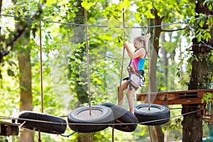 Child in adventure park. Kids climbing rope trail.