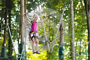 Child in adventure park. Kids climbing rope trail.