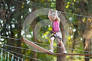 Child in adventure park. Kids climbing rope trail.