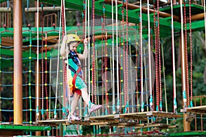 Child in adventure park. Kids climbing rope trail.