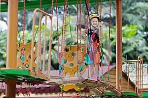 Child in adventure park. Kids climbing rope trail.