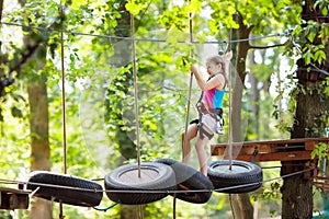 Child in adventure park. Kids climbing rope trail. photo