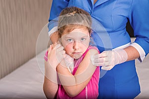 The child is afraid to be vaccinated. A gloved nurse applies medical cotton to the childÃ¢â¬â¢s shoulder. Not happy and scared face