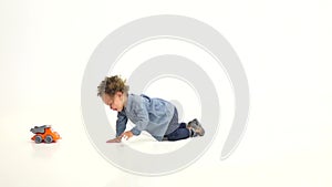 Child of an African American crawls towards a toy. White background. Slow motion