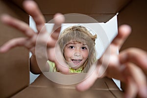 Child age 10 year opens carton box and pulling out gift from it. Small boy looking in parcel box and happy to receiving