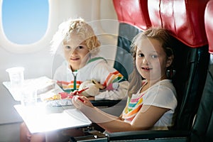 Child in airplane window seat. Kids flight meal. Children fly. Special inflight menu, food and drink for baby and kid. Girl and