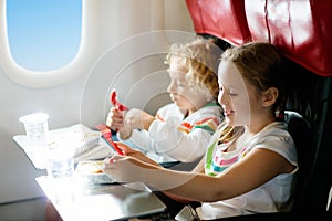 Child in airplane window seat. Kids flight meal. Children fly. Special inflight menu, food and drink for baby and kid. Girl and photo