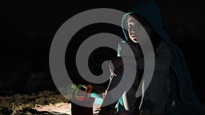 Child alone on a sandy beach against a black background on summer night