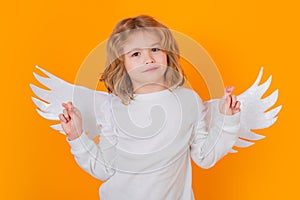 Child angel crossed fingers with lucky and hope, good luck. Valentine's day. Blonde cute child with angel wings on a