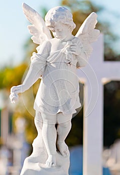 Child angel statue leaning in a cross