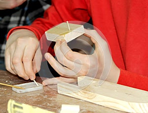 The child applies glue to the blank. Children `s master class on manufacturing of wooden ship