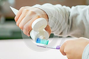 Child apply toothbrush and toothpaste on blurred background