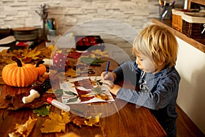 Child, applying leaves using glue, scissors, and paint, while doing arts and crafts at home