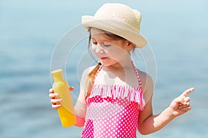 Child applying sunblock cream. girl holding sunscreen lotion in hand. Sun care on beach.