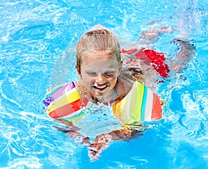 Child with armbands in swimming pool.