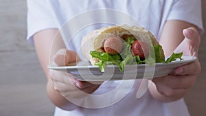 Child Arms Brings Plate Juicy American Hot Dog with Sausages and Lettuce Leaves