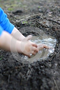 Child arms playing with mud, creating a pond with happiness