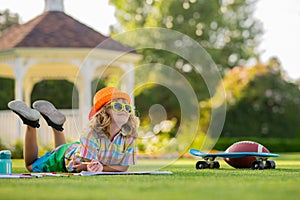 Child with artwork homework on playground. School kid drawing in summer park, painting art. Little painter draw pictures