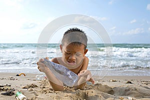 Child asian boy with plastic bottle at the beach.
