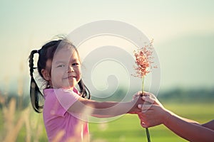 Child asian little girl giving grass flower to her mother