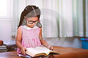 Child asian little girl put on eyeglasses reading a book