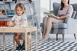 A child with Asperger Syndrome playing with wooden blocks during a therapeutic meeting with a therapist in a family support center photo