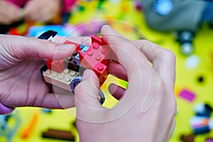 A child assembles a car from constructor parts