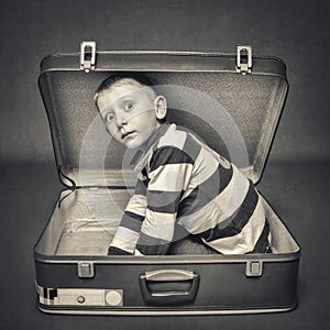 child with astonished expression in a suitcase