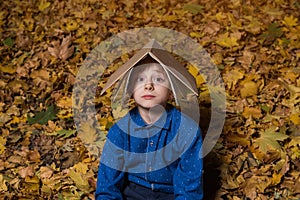 Child in autumn Park with book on head. Education concept. Relax or study