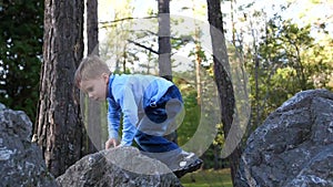 The child in the autumn Park fun playing and laughing, walking in the fresh air. The boy climbs large stones, he likes