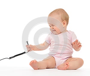 Child baby girl toddler sitting with wire cable expression of electric shock