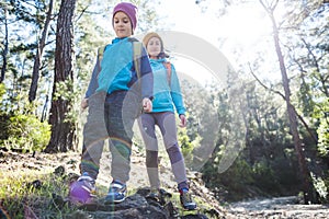 A child with a backpack walks in the forest with his mother