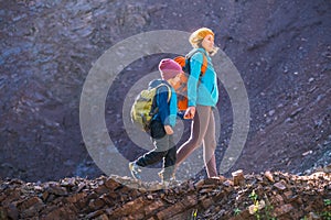 A child with a backpack walks in the forest with his mother