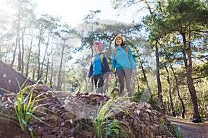 A child with a backpack walks in the forest with his mother