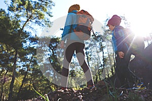 A child with a backpack walks in the forest with his mother