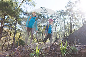 A child with a backpack walks in the forest with his mother