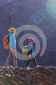 A child with a backpack walks in the forest with his mother